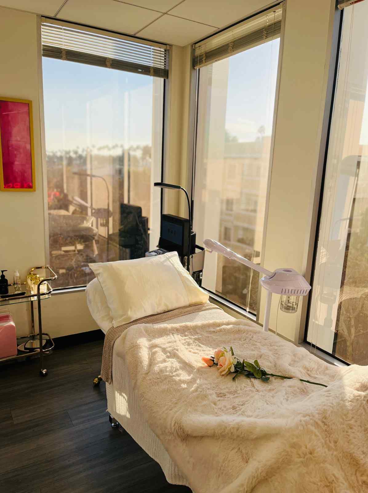 Luxury medical spa treatment room at Beverly Wilshire Aesthetics featuring a plush white facial bed, modern skincare equipment, and expansive views of Beverly Hills.